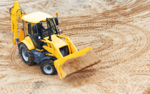 Image of a backhoe loader bucket scooping dirt for a construction project.