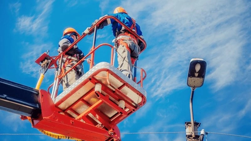 Municipal maintenance is repairing street lights at high altitude with boom lift.