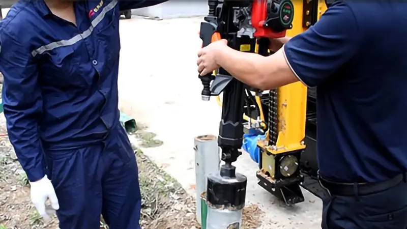 Construction workers are using a handheld pile driver to drive guardrail piles