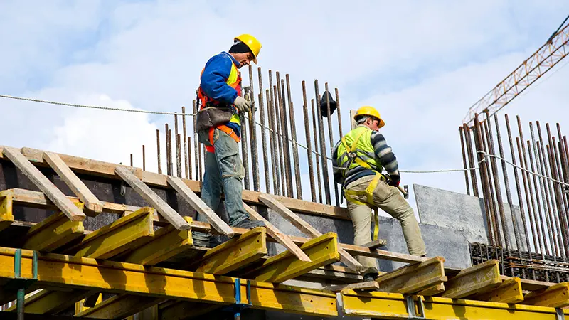 Workers examining construction work at a site, surrounded by various equipment and machinery.