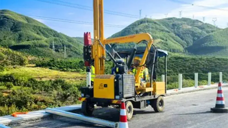 Wheel pile driver is installing highway guardrail piles