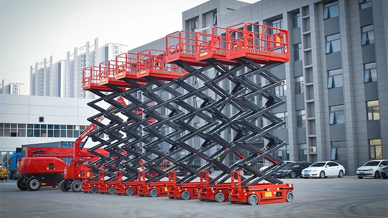 Row of red scissor lifts lined up in an industrial yard.