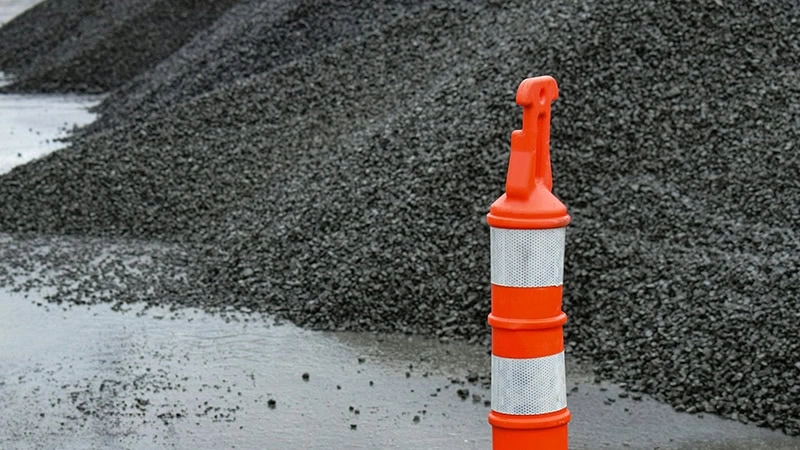 an orange and white traffic cone next to a pile of gravel
