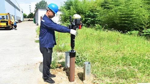 An operator is using a handheld pile driver